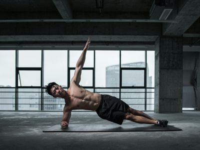 Athletic man performing a steady plank in a dark gym