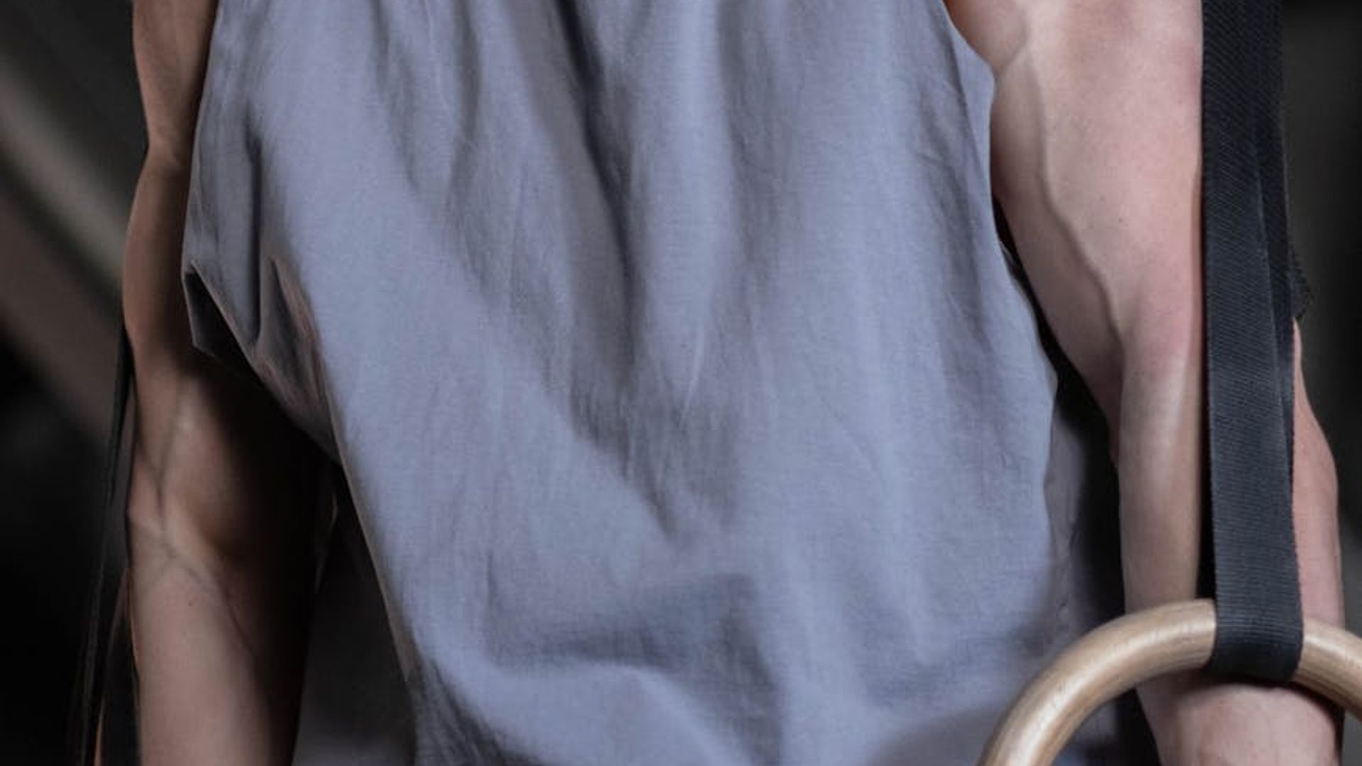 Man performing steady strength exercises in a dark modern gym environment