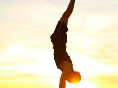 Silhouetted figure of a man doing strength exercises at sunset